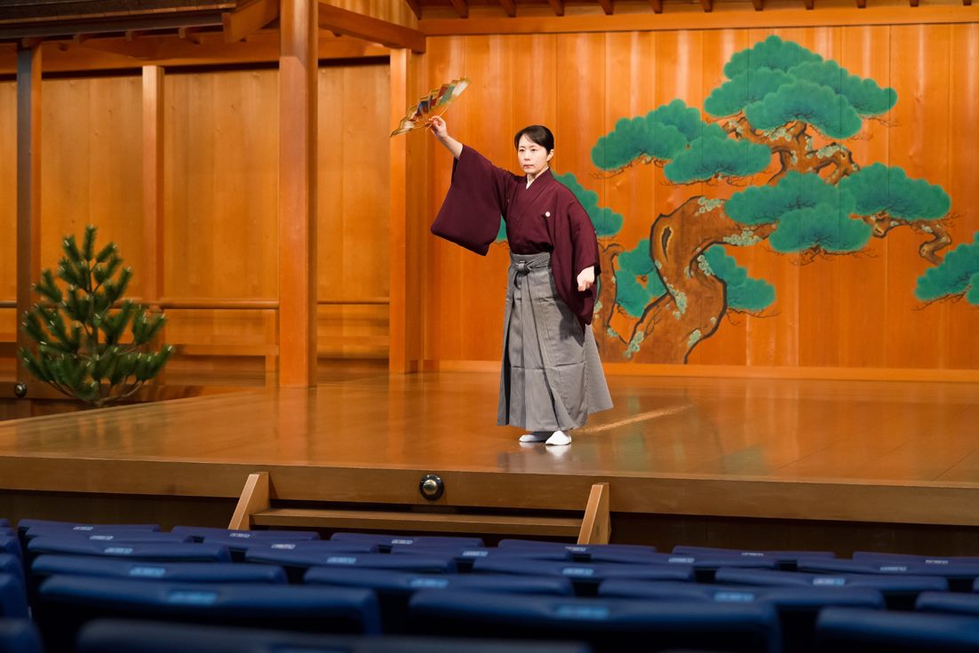 The Noh performer dancing shimai with a golden fan on stage